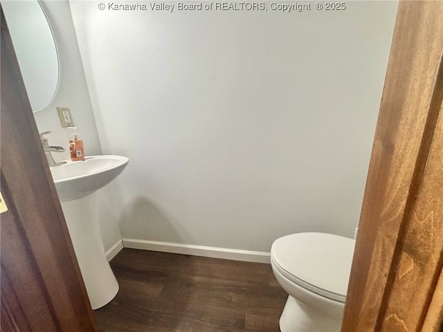 bathroom with baseboards, a sink, wood finished floors, and toilet