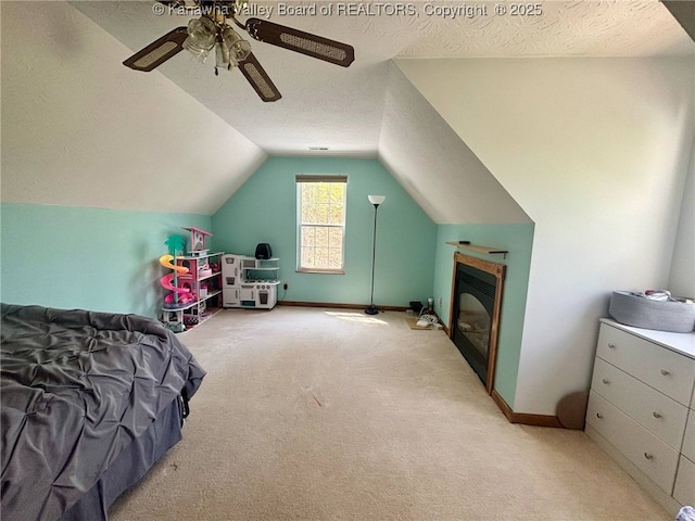bedroom with lofted ceiling, baseboards, light colored carpet, a textured ceiling, and a ceiling fan