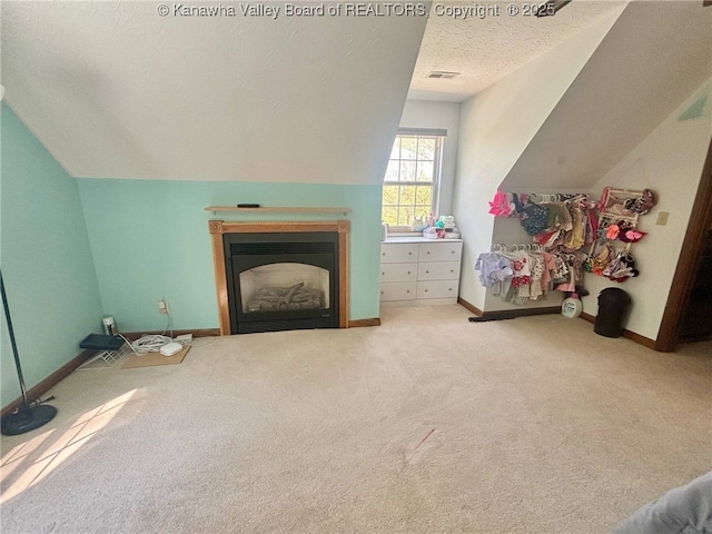 interior space featuring visible vents, carpet floors, lofted ceiling, baseboards, and a textured ceiling