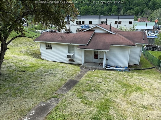 rear view of house featuring fence, covered porch, cooling unit, a shingled roof, and a lawn