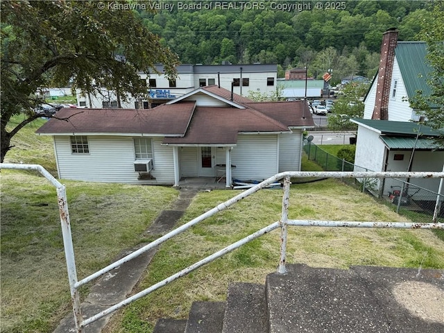 view of front facade with a shingled roof, a front lawn, and a fenced backyard