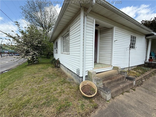 view of side of home featuring a yard and entry steps