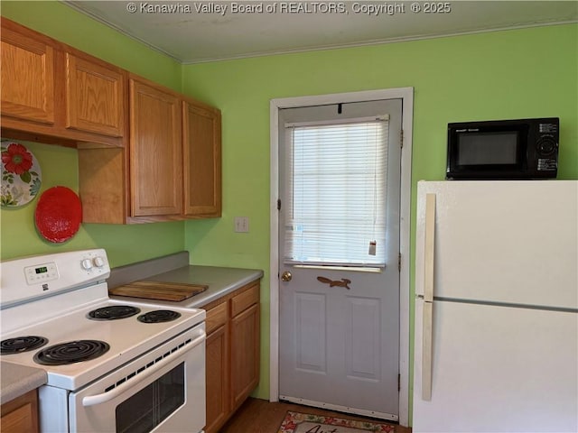 kitchen featuring light countertops, ornamental molding, white appliances, and wood finished floors