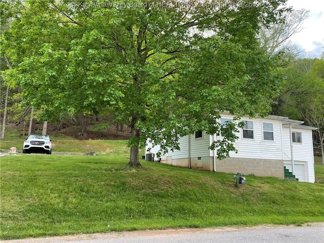 view of property exterior with central air condition unit, an attached garage, and a yard