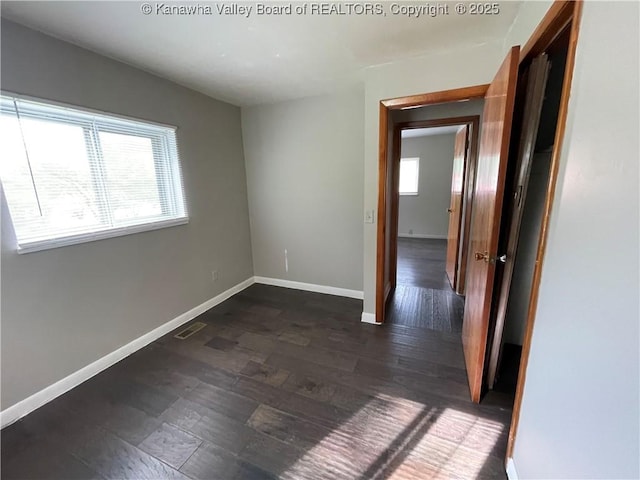 unfurnished room featuring baseboards and dark wood finished floors