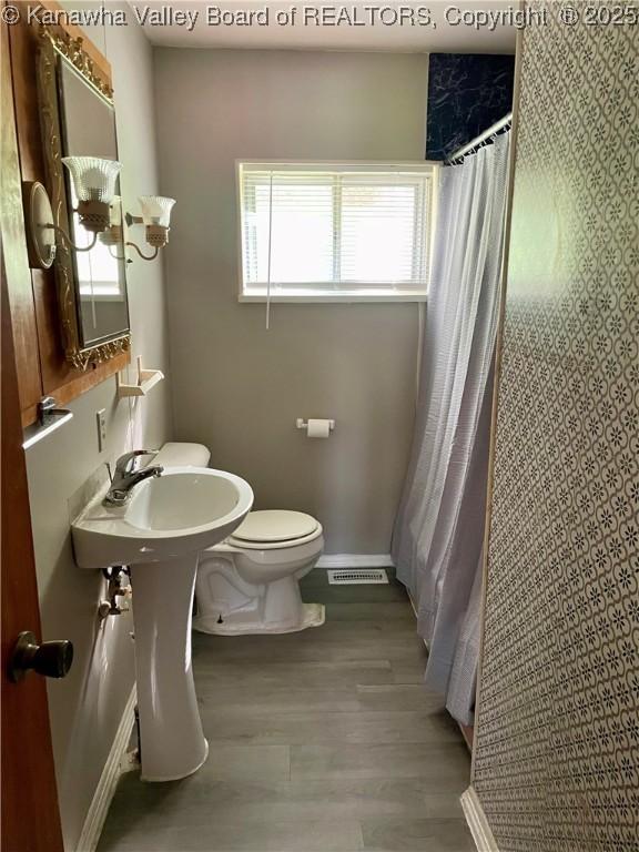 bathroom featuring visible vents, wood finished floors, curtained shower, toilet, and baseboards