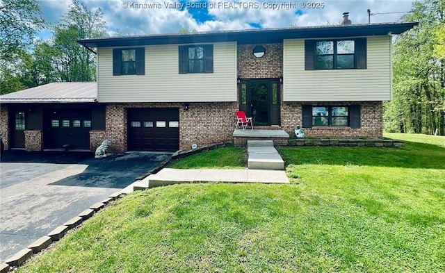 split foyer home with an attached garage, driveway, brick siding, and a front yard