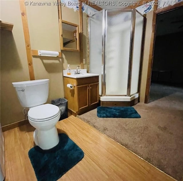 full bath with vanity, a shower stall, toilet, and wood finished floors