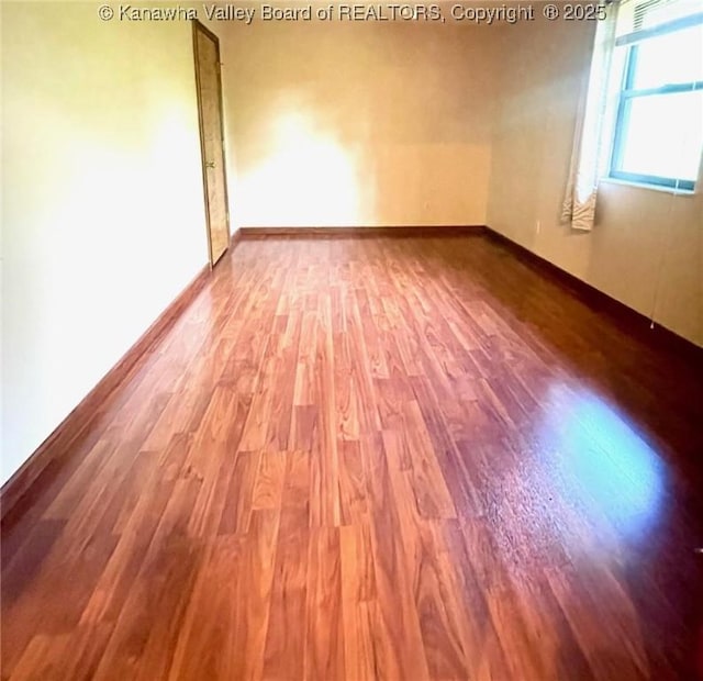 unfurnished room with baseboards and wood finished floors