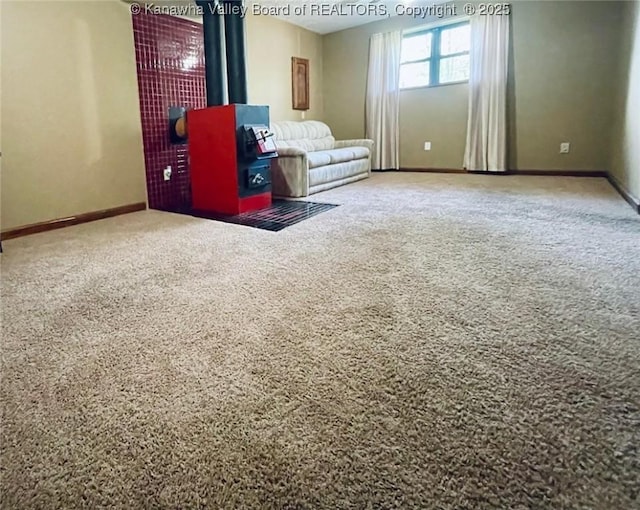 living area with baseboards, a wood stove, and carpet