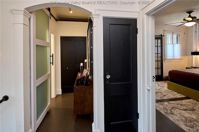 corridor featuring arched walkways and wood finished floors