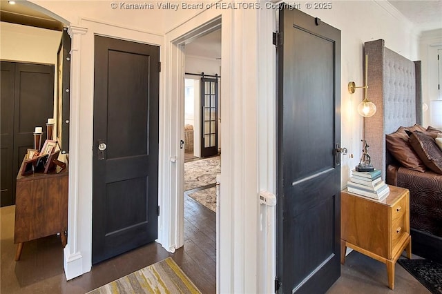 interior space featuring crown molding, dark wood finished floors, and a barn door