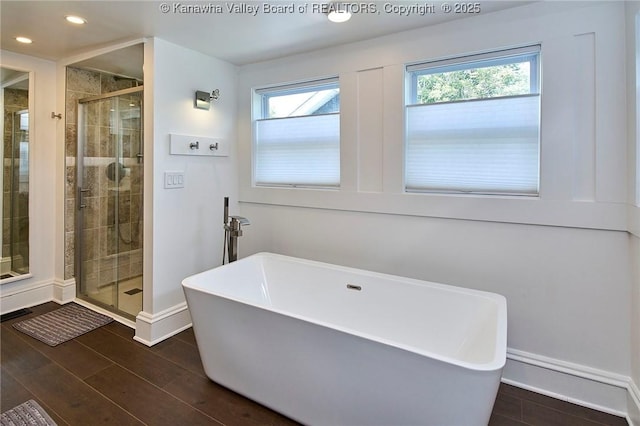 bathroom with recessed lighting, baseboards, a freestanding tub, wood finished floors, and a stall shower