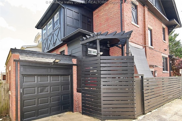 view of side of home with fence, a pergola, driveway, and brick siding