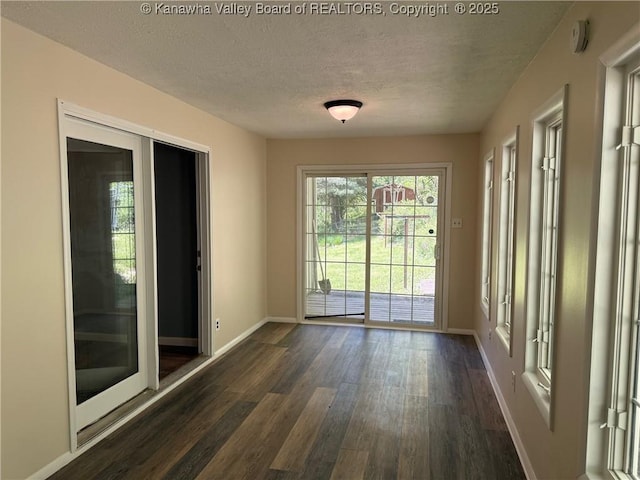 doorway to outside with baseboards, a textured ceiling, and dark wood-type flooring