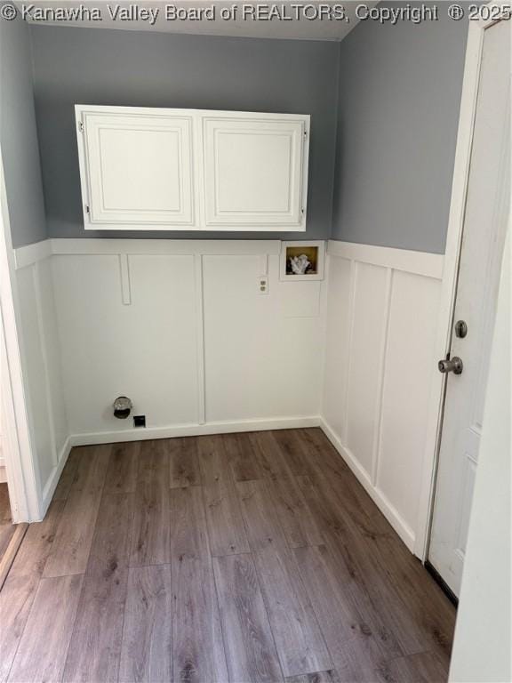 washroom with a decorative wall, wood finished floors, a wainscoted wall, cabinet space, and washer hookup