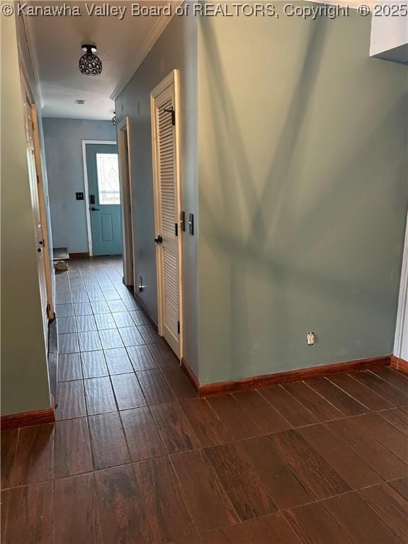 corridor with baseboards, ornamental molding, and wood tiled floor