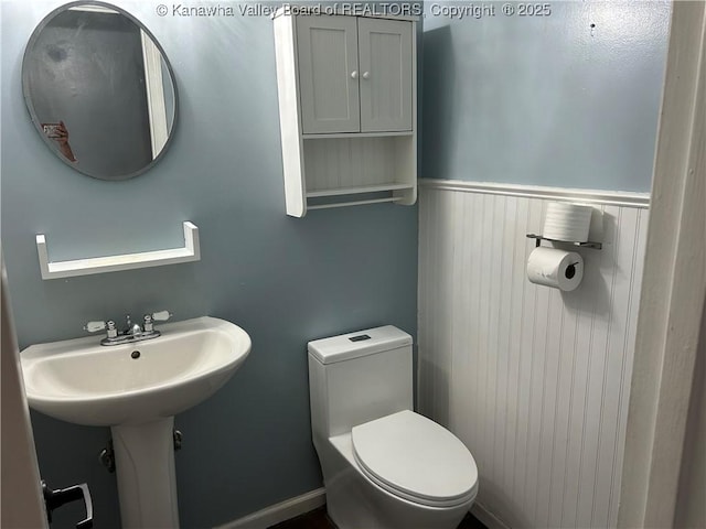 half bathroom with a wainscoted wall and toilet