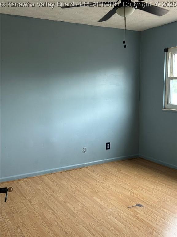 unfurnished room with light wood-style floors, a textured ceiling, baseboards, and ceiling fan