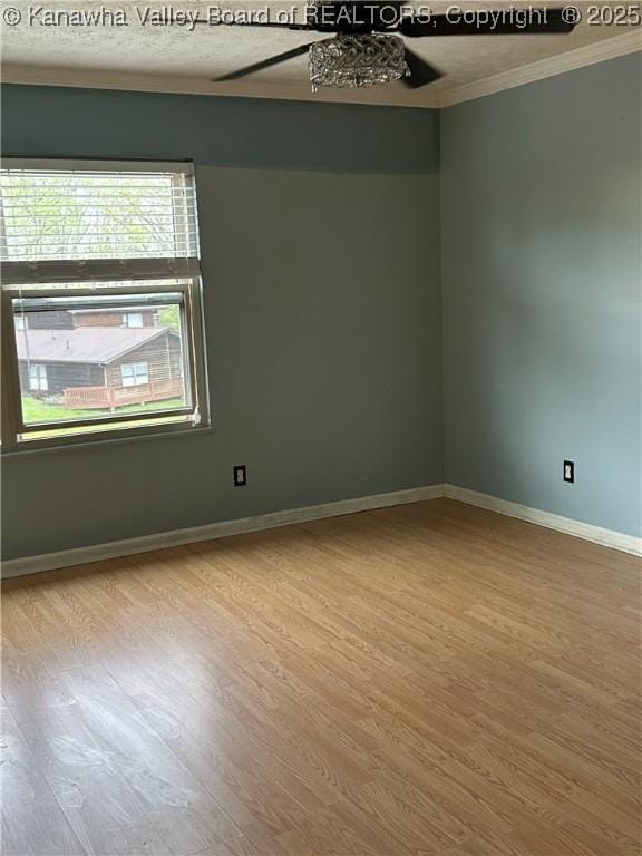 spare room with crown molding, baseboards, ceiling fan, and wood finished floors