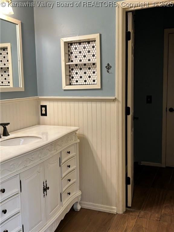bathroom with vanity, wood finished floors, and a wainscoted wall