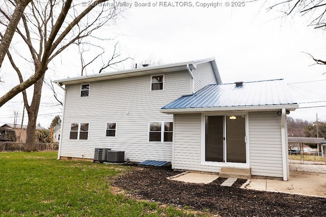 rear view of house with a lawn, fence, cooling unit, and metal roof