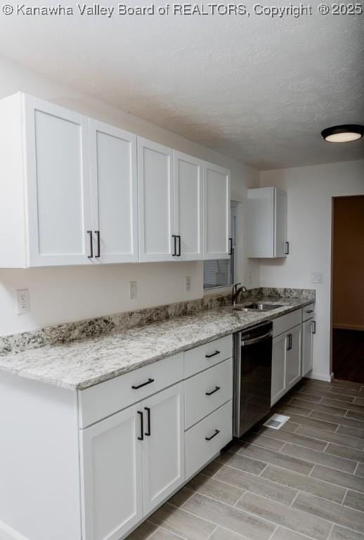 kitchen featuring dishwashing machine, light wood-type flooring, a textured ceiling, white cabinetry, and a sink