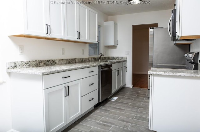 kitchen with white cabinets, appliances with stainless steel finishes, a sink, and wood tiled floor