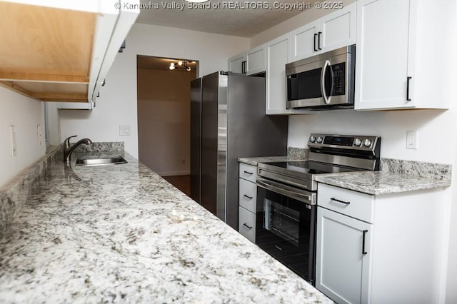 kitchen featuring light stone counters, a sink, white cabinetry, and appliances with stainless steel finishes