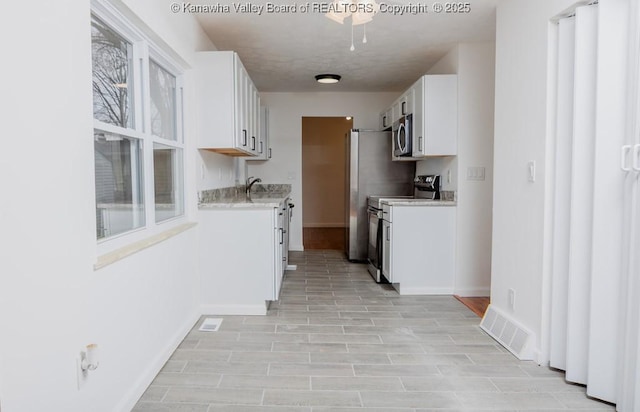 kitchen featuring visible vents, baseboards, light countertops, white cabinetry, and appliances with stainless steel finishes
