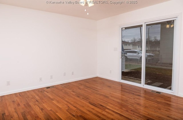 empty room with baseboards, visible vents, and wood finished floors