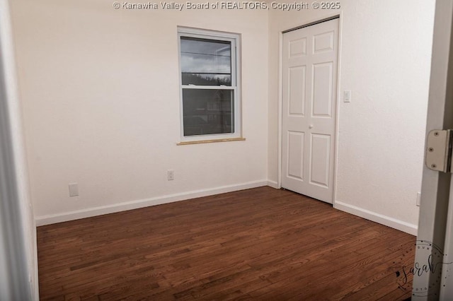 unfurnished bedroom featuring baseboards and dark wood-style floors
