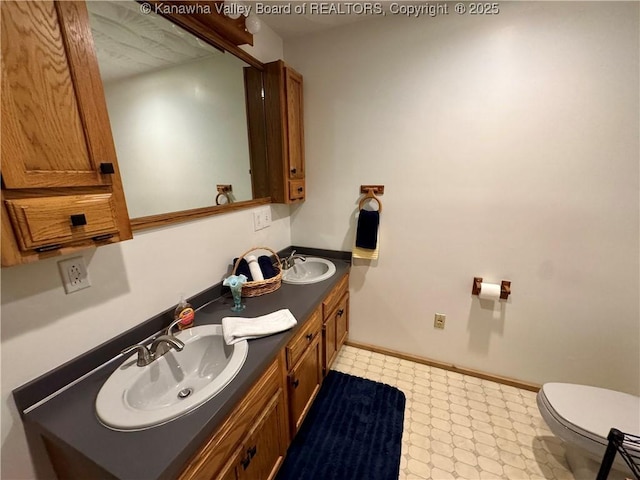 bathroom with double vanity, a sink, tile patterned floors, and toilet