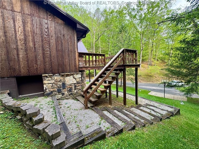 exterior space featuring a view of trees, a wooden deck, and stairs