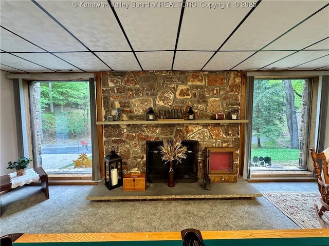unfurnished living room featuring a healthy amount of sunlight, a fireplace, carpet flooring, and a paneled ceiling