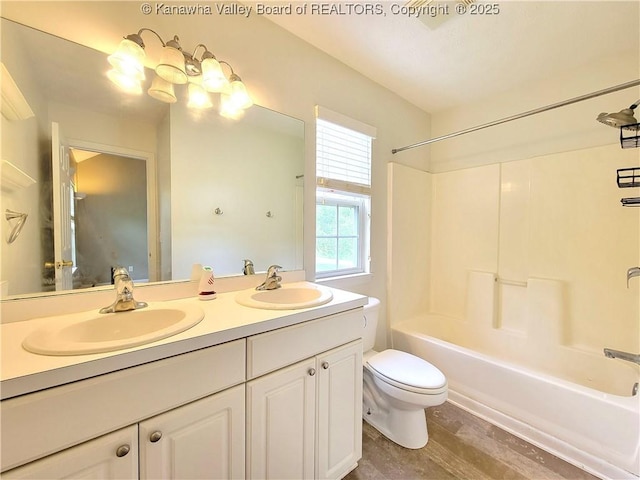 bathroom featuring double vanity, a sink, shower / bath combination, and toilet