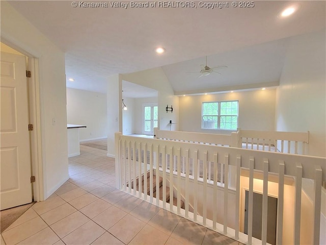 hall featuring lofted ceiling, baseboards, recessed lighting, tile patterned floors, and an upstairs landing