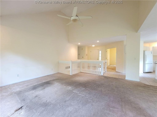 unfurnished room featuring baseboards, high vaulted ceiling, light colored carpet, a ceiling fan, and light tile patterned floors