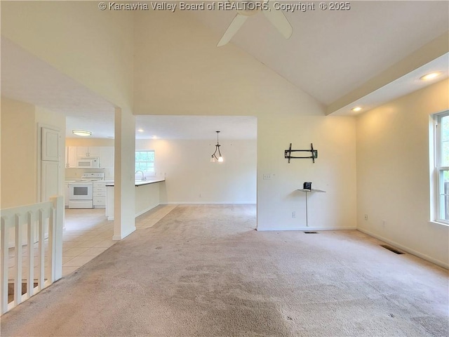 empty room with light colored carpet, high vaulted ceiling, recessed lighting, baseboards, and light tile patterned floors