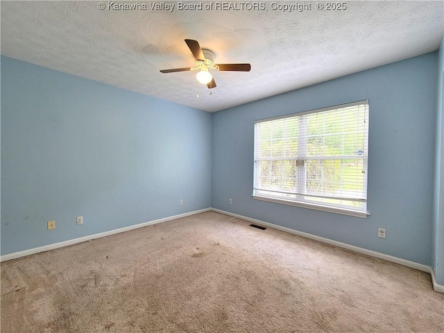 empty room with carpet floors, baseboards, a ceiling fan, and visible vents