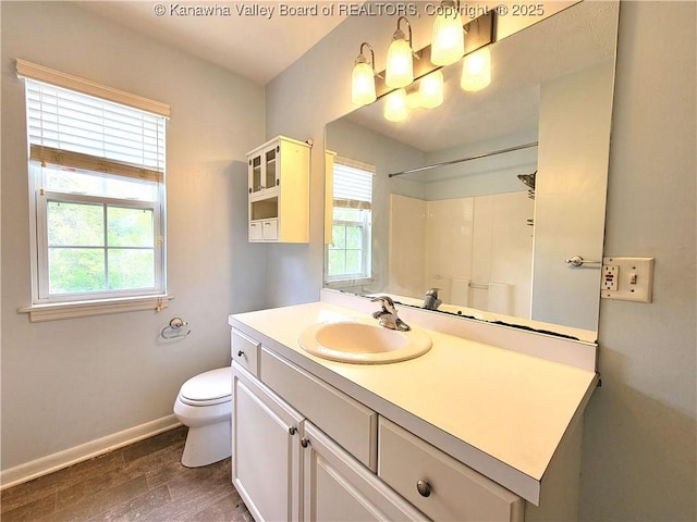 bathroom with baseboards, toilet, wood finished floors, and a wealth of natural light