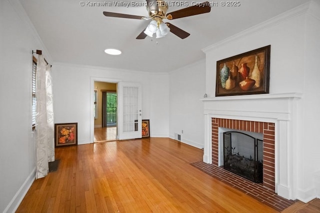 unfurnished living room with ceiling fan, crown molding, a fireplace, wood finished floors, and baseboards