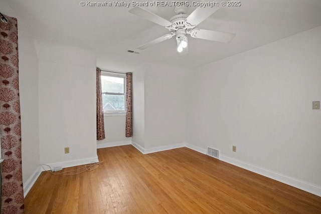 empty room featuring a ceiling fan, baseboards, visible vents, and light wood-type flooring