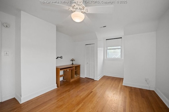 unfurnished bedroom with a ceiling fan, visible vents, vaulted ceiling, baseboards, and light wood-style flooring