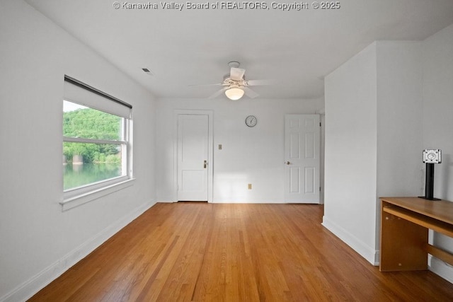 unfurnished room with light wood-type flooring, a ceiling fan, and baseboards