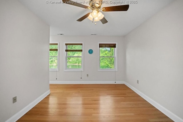 empty room featuring light wood-style floors, baseboards, ceiling fan, and visible vents