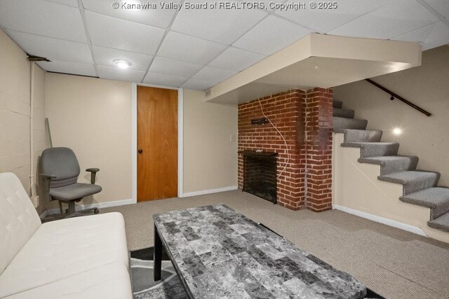 living area with carpet floors, baseboards, a paneled ceiling, and a fireplace