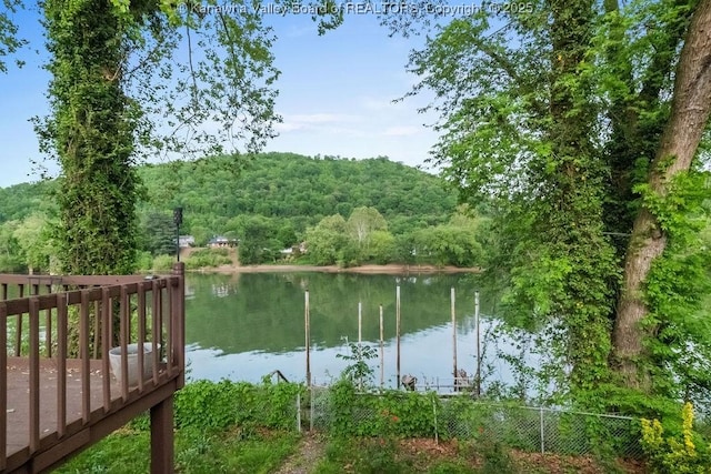 property view of water featuring fence and a forest view