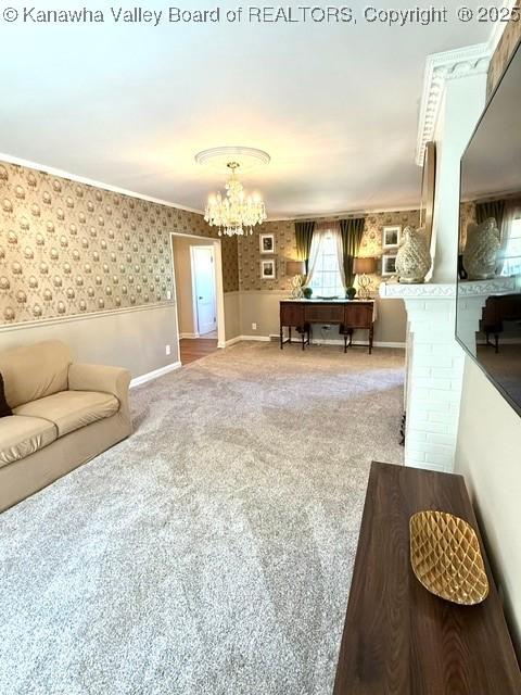 carpeted living area featuring wallpapered walls, a chandelier, and a wainscoted wall