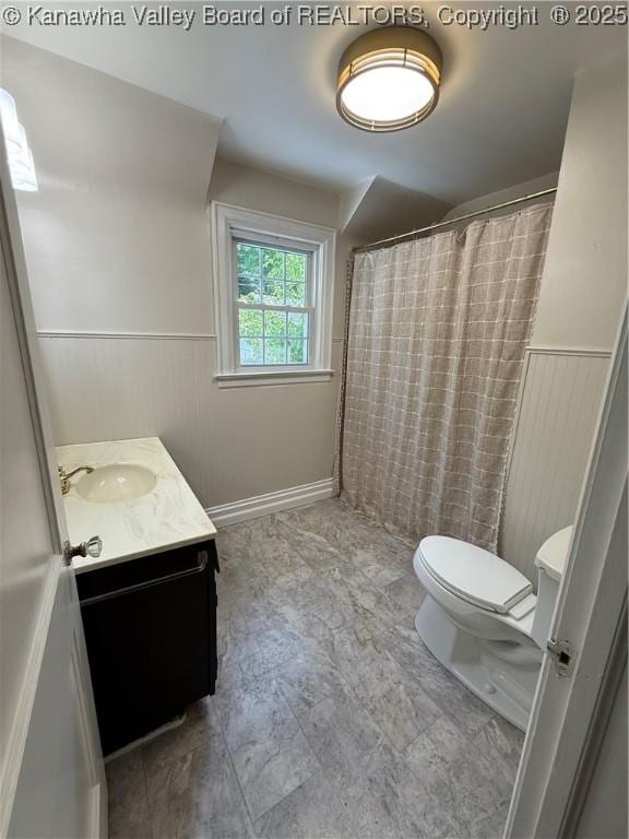 full bathroom with a shower with curtain, a wainscoted wall, vanity, and toilet